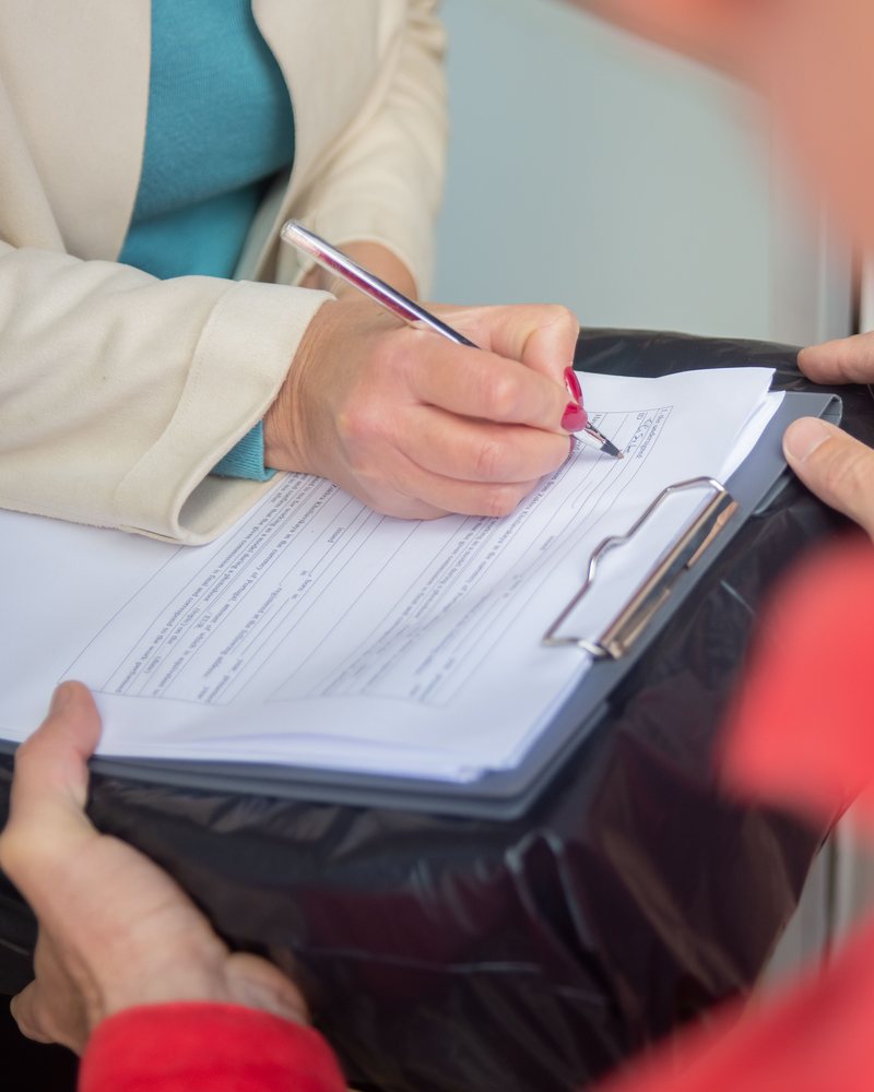 Shipping paperwork being signed on a clipboard at handover