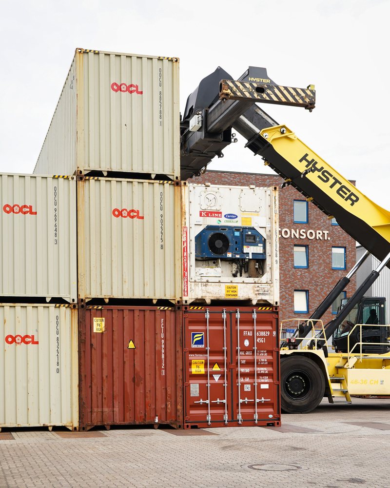 Shipping containers stacked in a yard beside a reach stacker